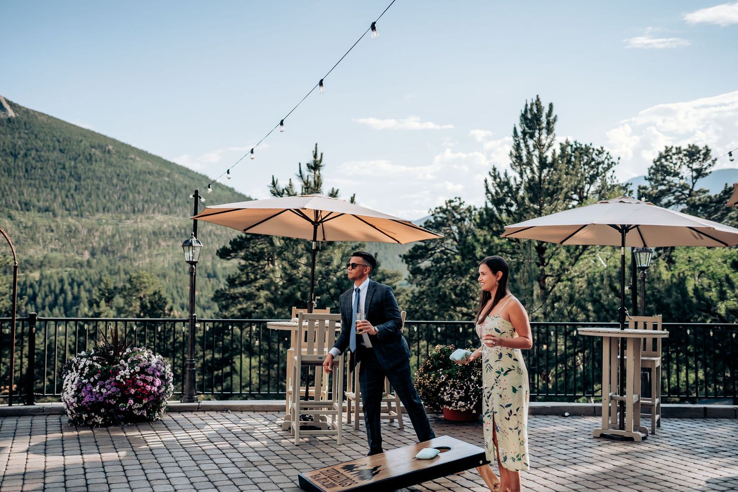 An outdoor wedding ceremony setup with patio umbrellas and string lights against mountain scenery.