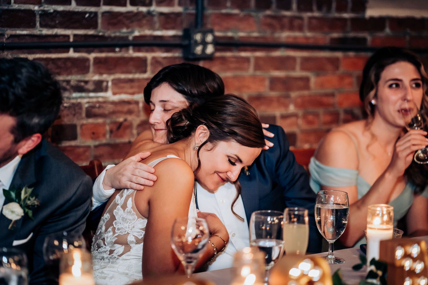 Candid reception moment shows guests reacting with emotion at elegantly set dinner table.