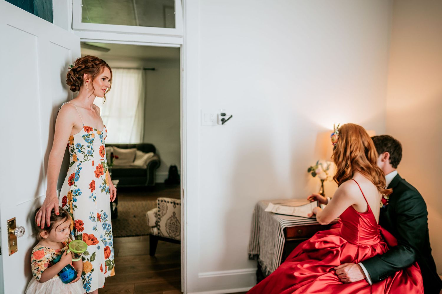 Intimate moment captured during wedding preparations with red dress and floral print details.