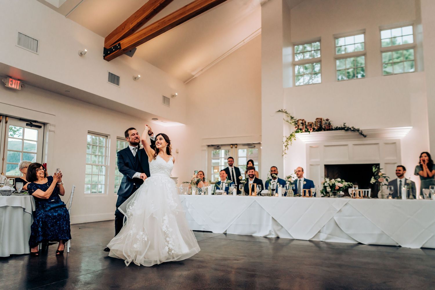 Wedding couple's first dance in reception hall with guests watching from head table.