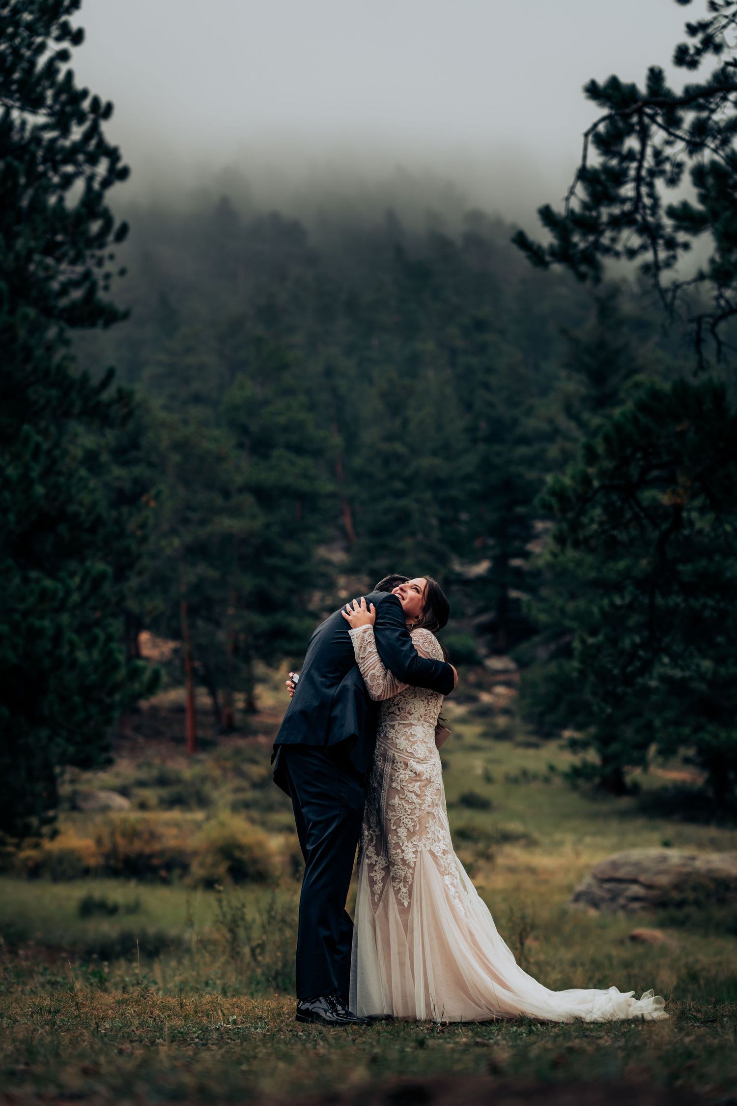 A romantic dance in a lace gown and suit against a moody forest backdrop.