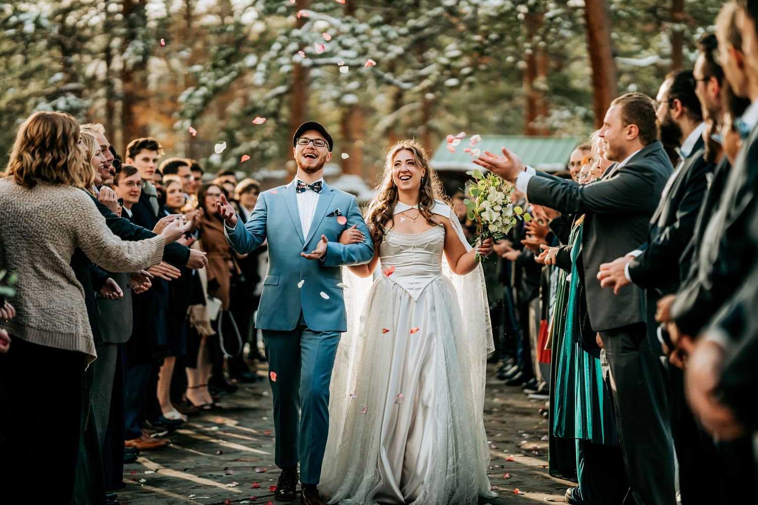 Wedding ceremony exit with guests celebrating in an outdoor forest setting.
