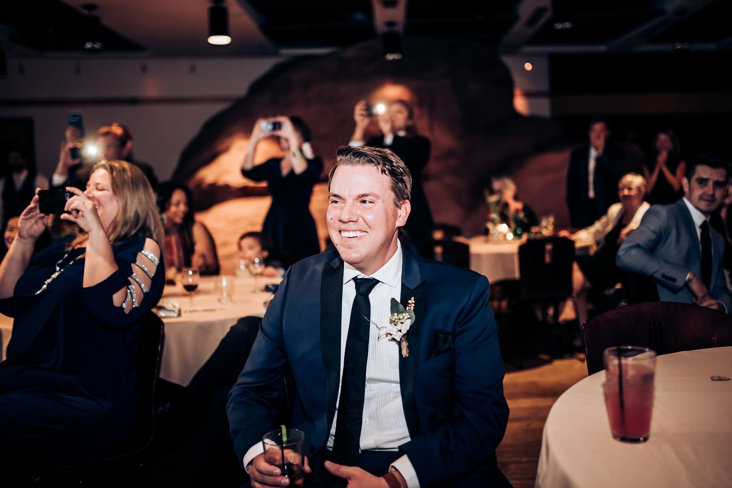 Guest in formal attire enjoys entertainment during an indoor wedding reception.