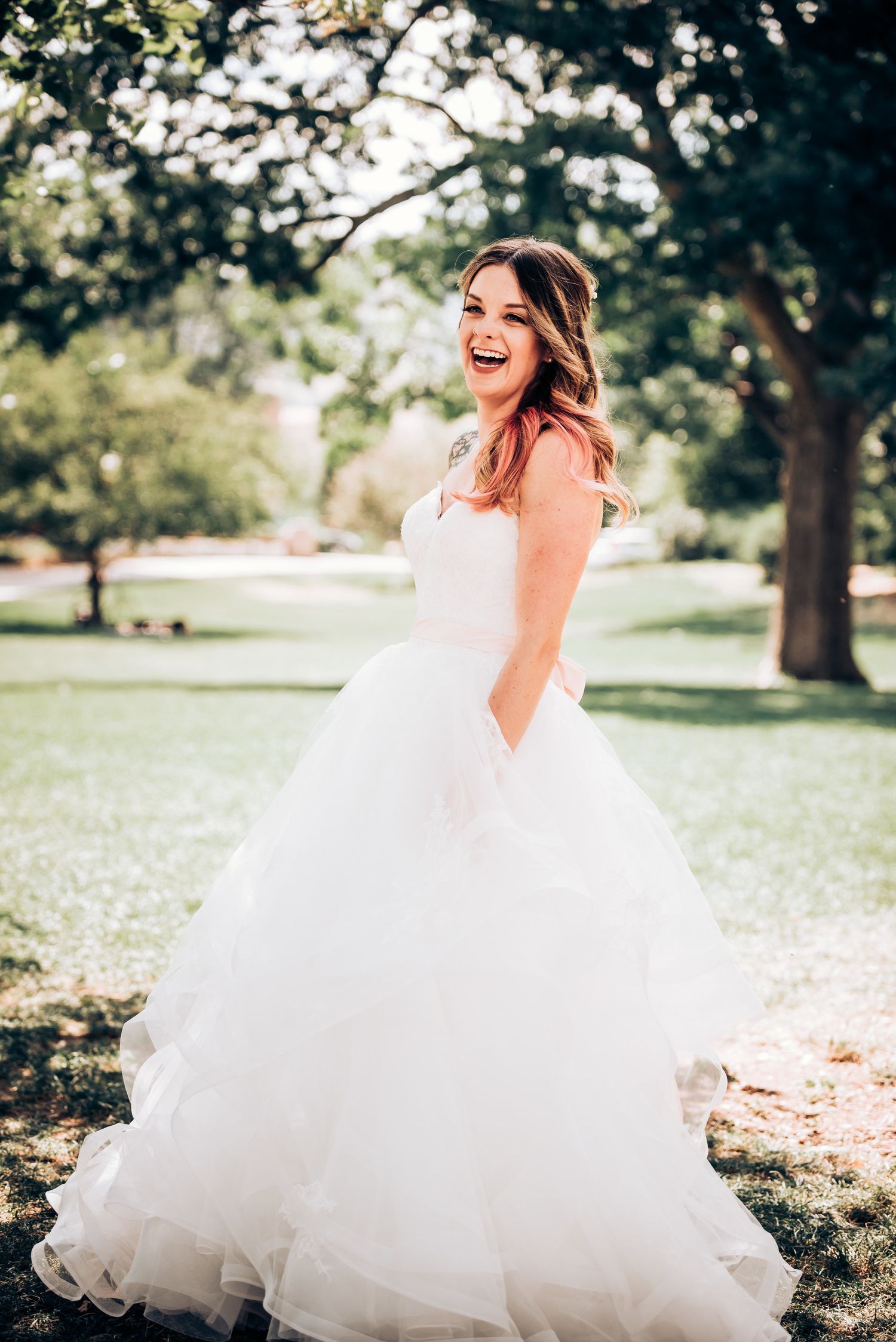 A flowing white ballgown wedding dress sparkles in natural outdoor lighting.