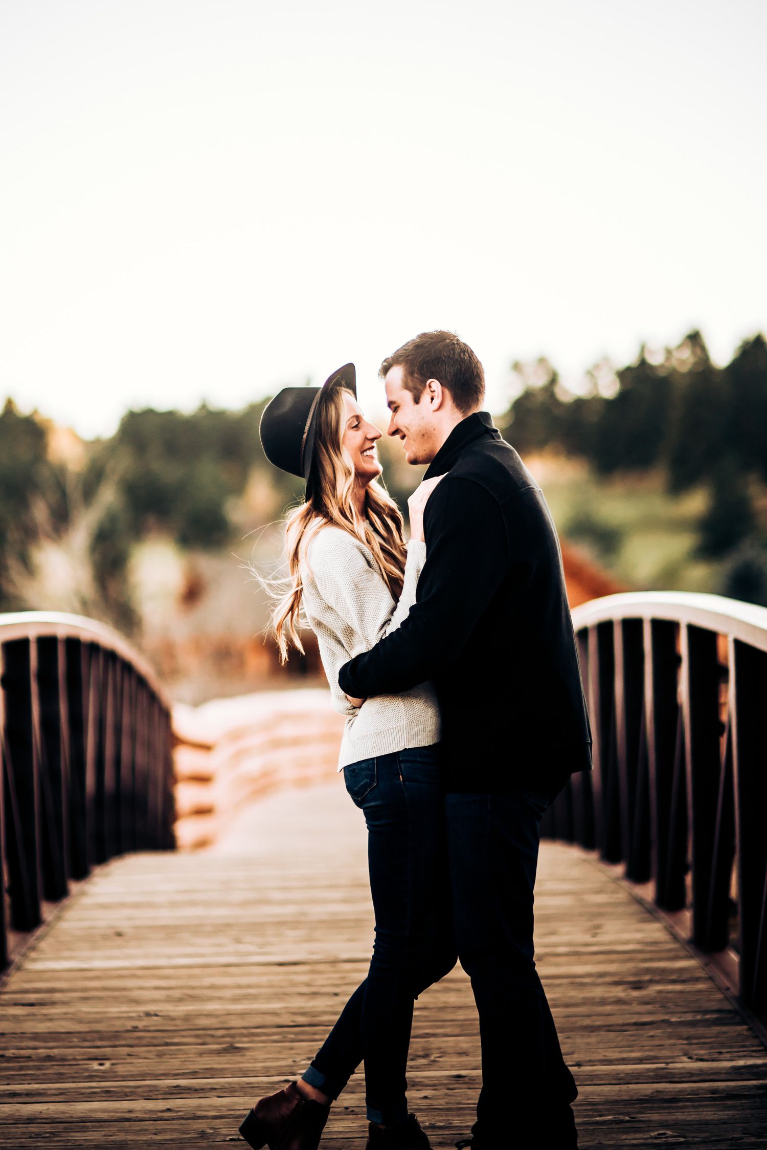 Romantic moment shared on wooden bridge during sunset photoshoot.