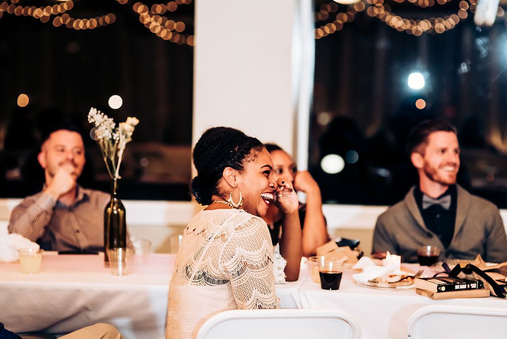 Wedding guests enjoy a joyful reception dinner under string lights and elegant decor.
