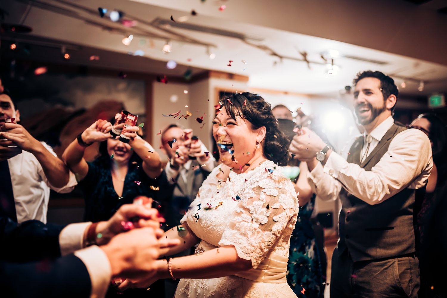 Wedding celebration showing enthusiastic dancing and crowd interaction at an indoor reception venue.