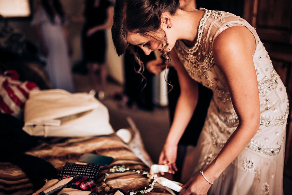 Someone in a beaded dress sorts through wedding accessories on a table.