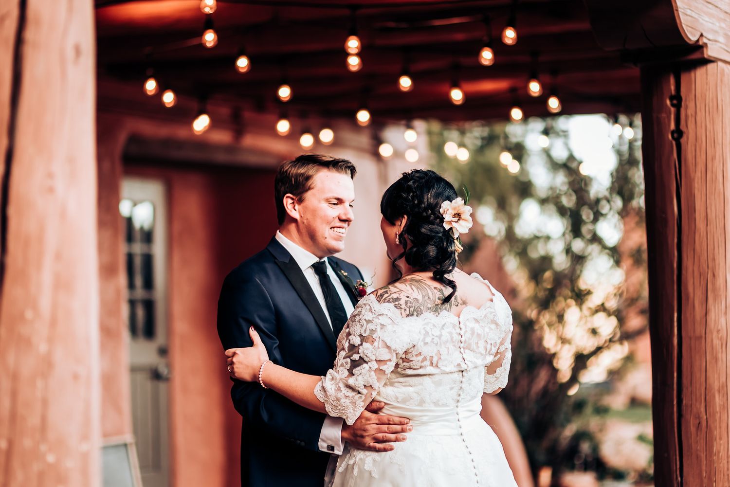 Dancing couple share romantic moment on patio with string lights overhead.