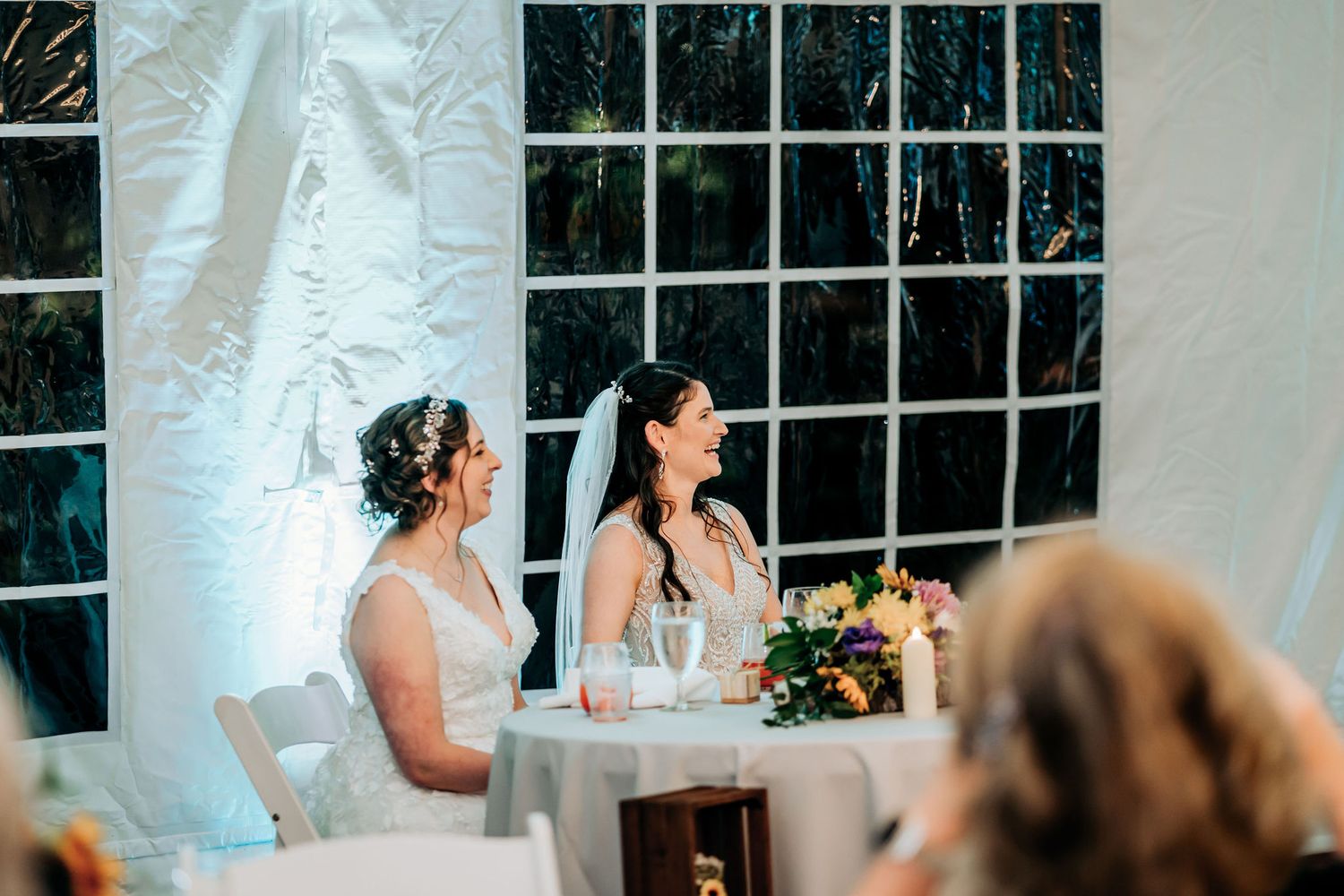 Two people in formal attire seated at an elegantly decorated wedding reception table.