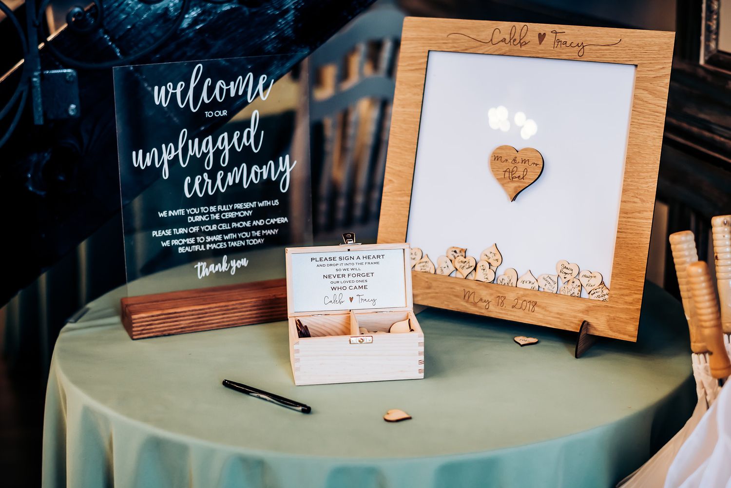 Wedding welcome display featuring unplugged ceremony sign and guest book on round table.