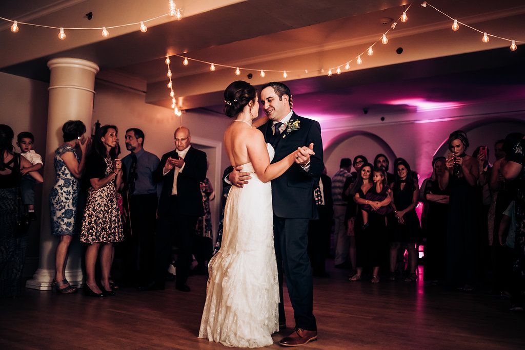 Romantic first dance moment under warm reception lighting and string lights.