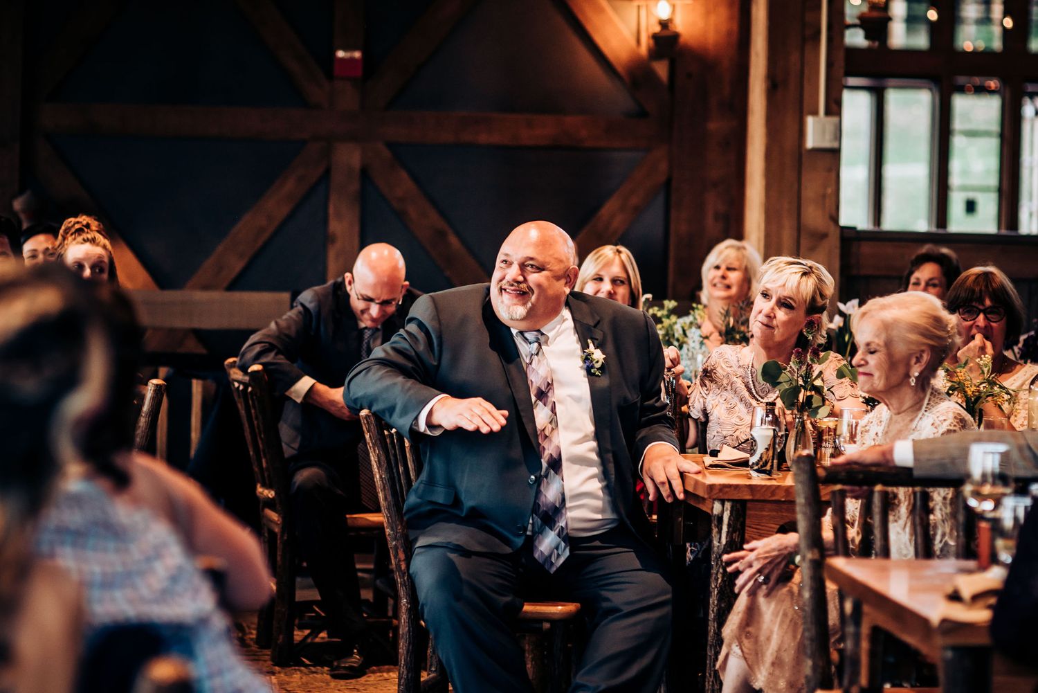 Wedding guests laughing and celebrating at tables during reception dinner.