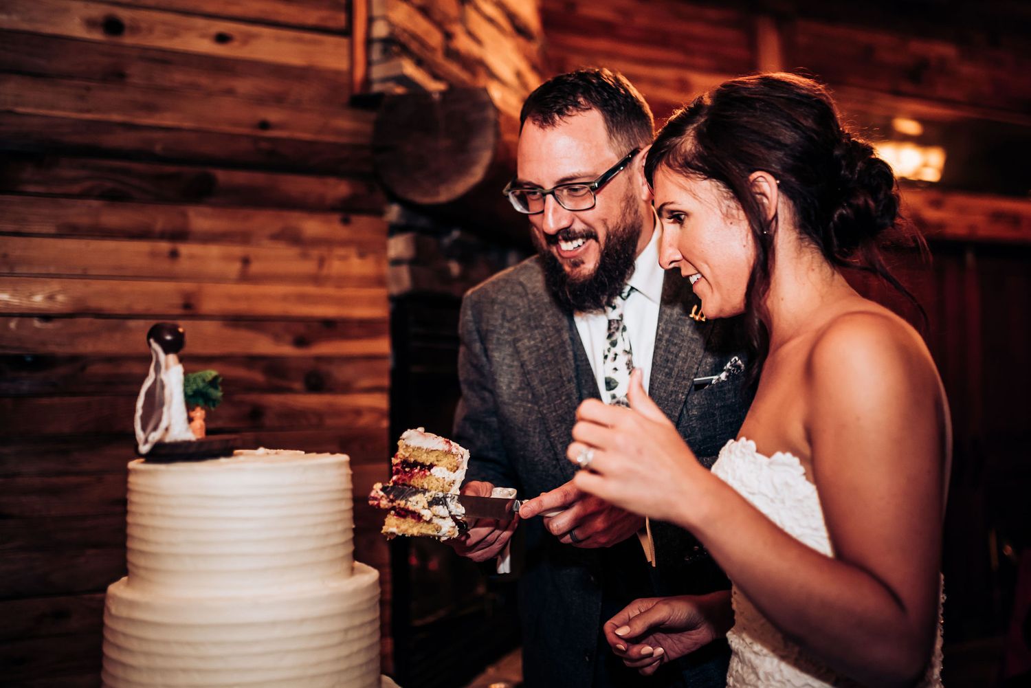 Newlyweds enjoying their wedding cake together at rustic reception venue.