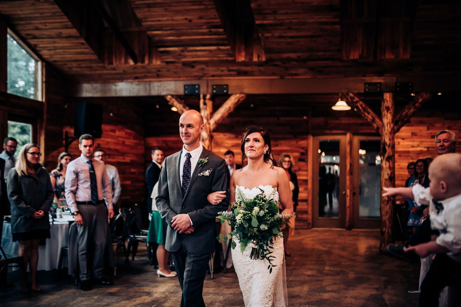 A joyful wedding entrance in a rustic wooden venue.