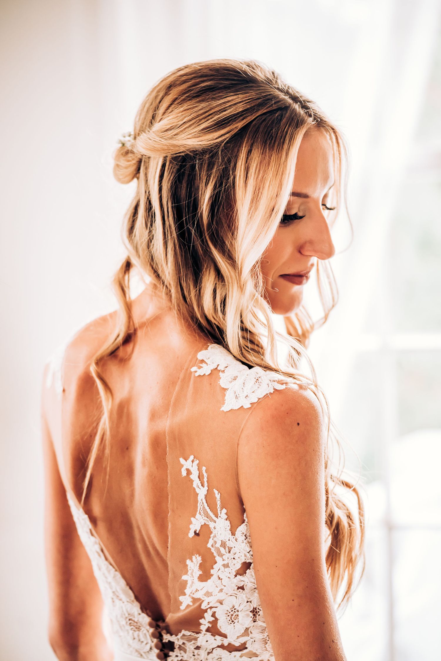 Detailed back of wedding dress features intricate lace appliques and sheer design.