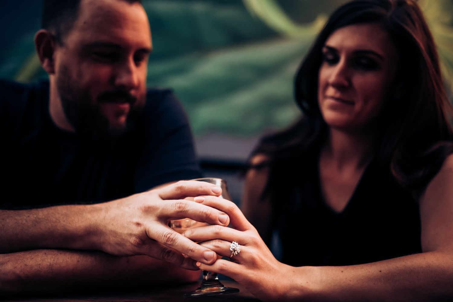Couple holding hands intimately in dimly lit setting.