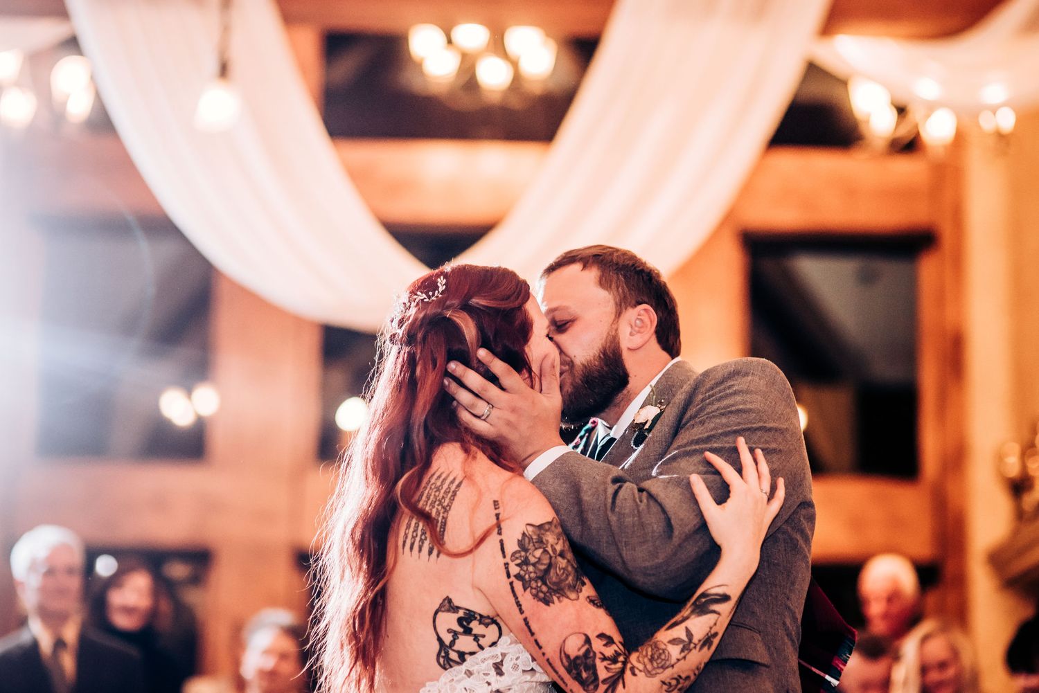 Intimate dance moment between couple under warm lighting and white fabric decorations.