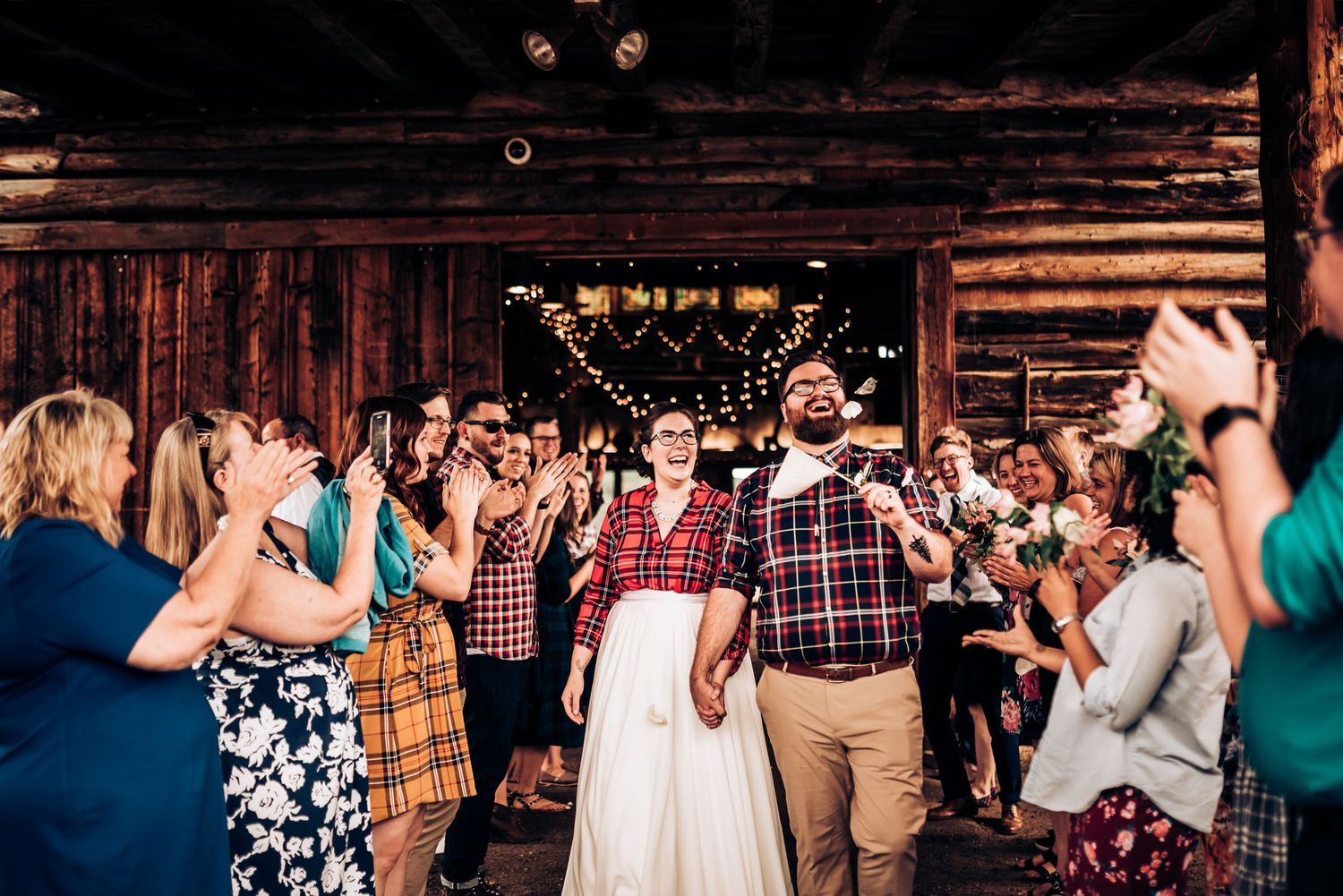 Festive celebration scene in wooden barn venue with guests clapping and cheering.
