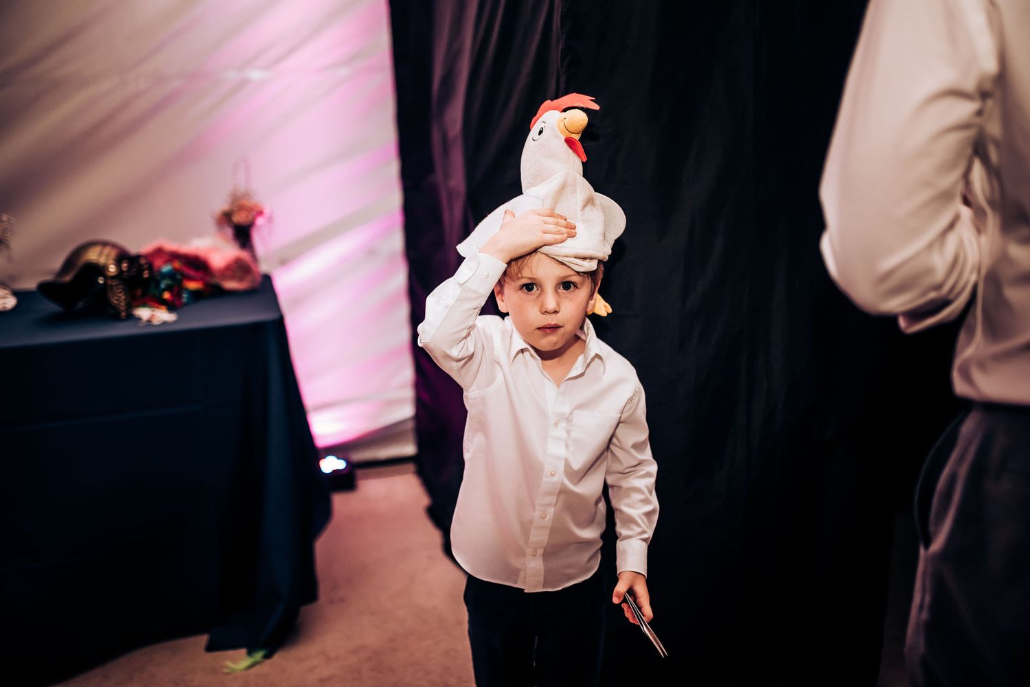 Young boy in white dress shirt dances energetically at wedding reception.