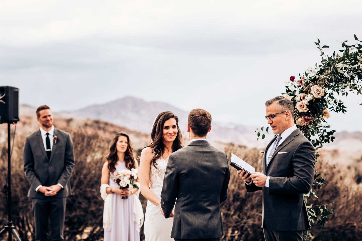 Wedding ceremony on a brick patio with mountains visible in the distance.