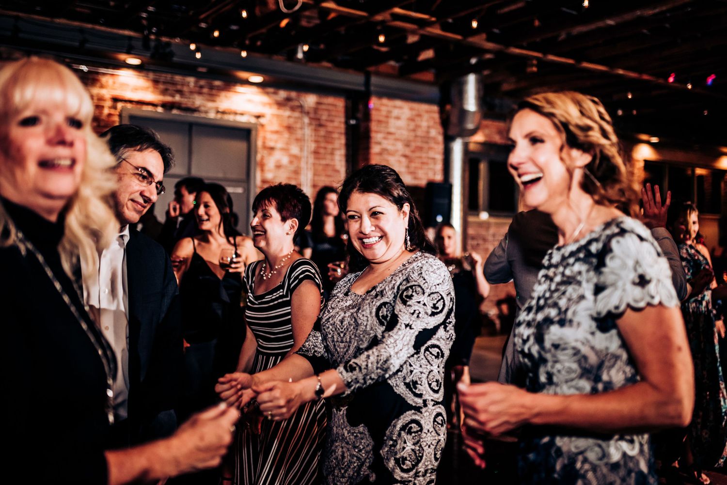 Group of guests laughing and enjoying themselves at an indoor celebration.