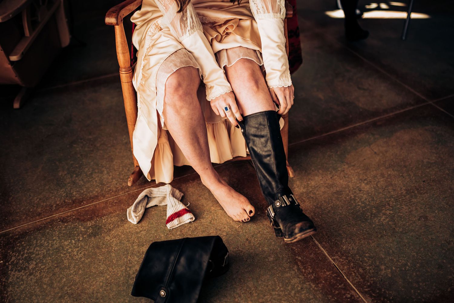 Person helping with footwear during wedding preparations on dark wooden floors.