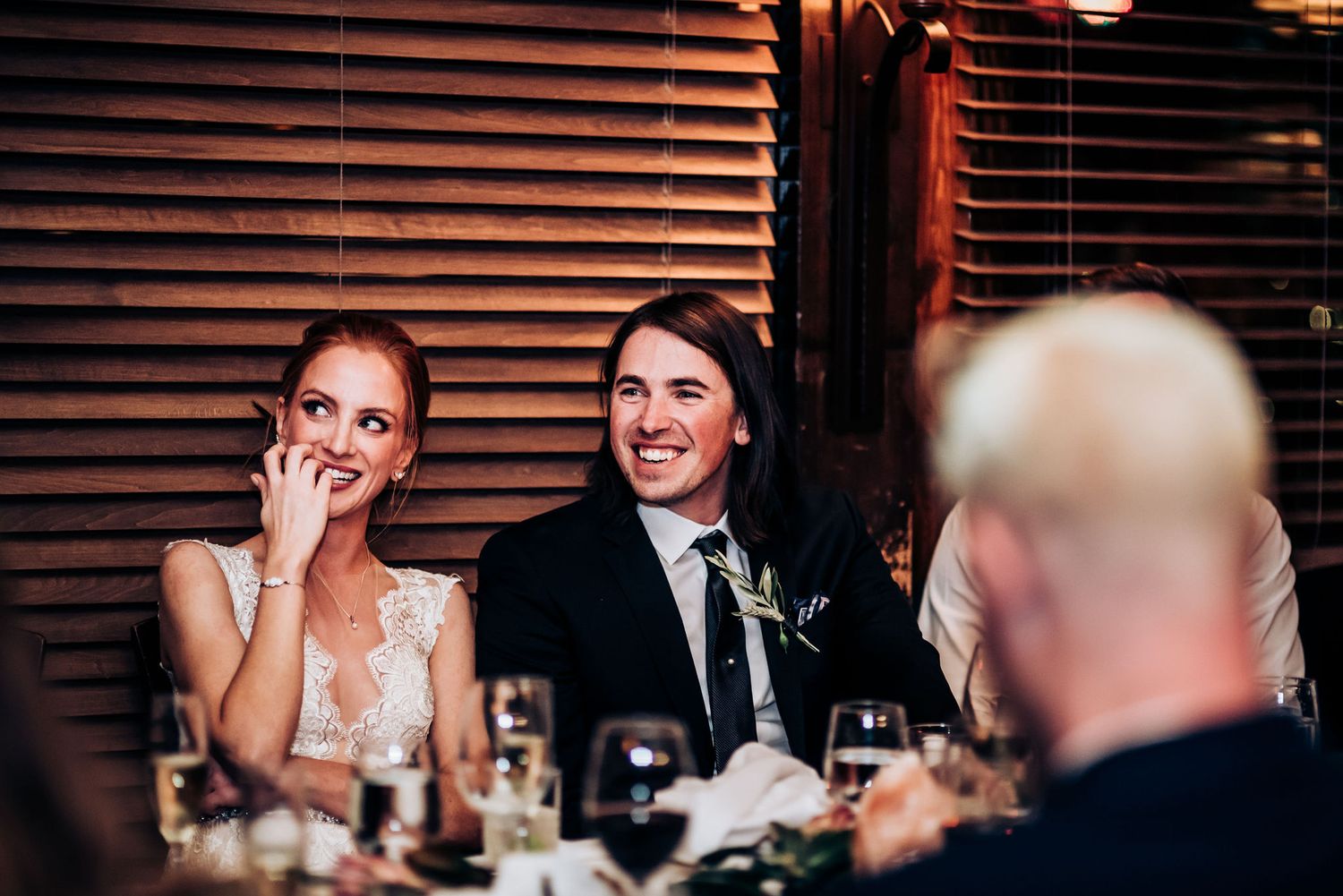 A couple reacts emotionally to speeches during their wedding reception dinner.