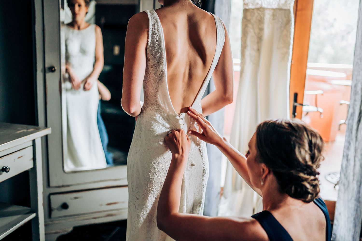 Behind-the-scenes moment of wedding dress preparation in dressing room.