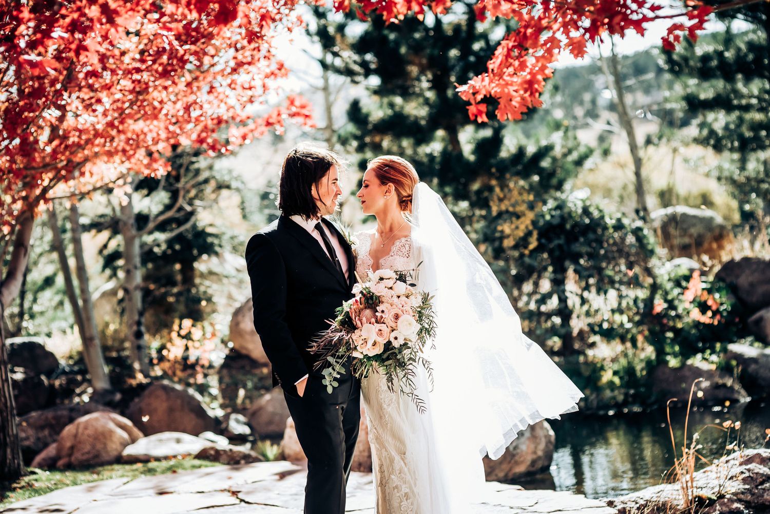 Romantic wedding portrait with stunning red fall foliage backdrop.