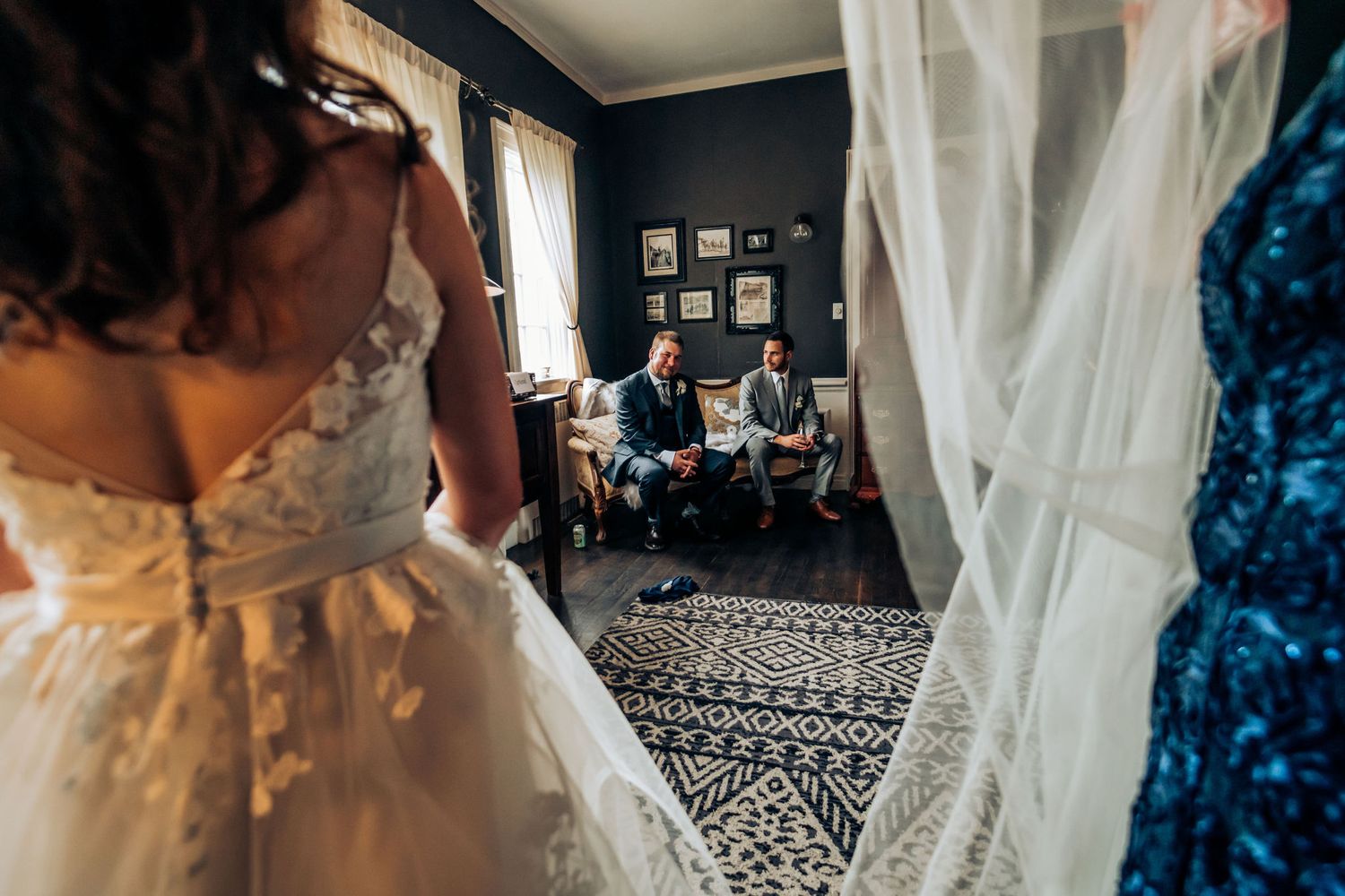 Artistic wedding photograph through white veils showing guests seated in dark room.