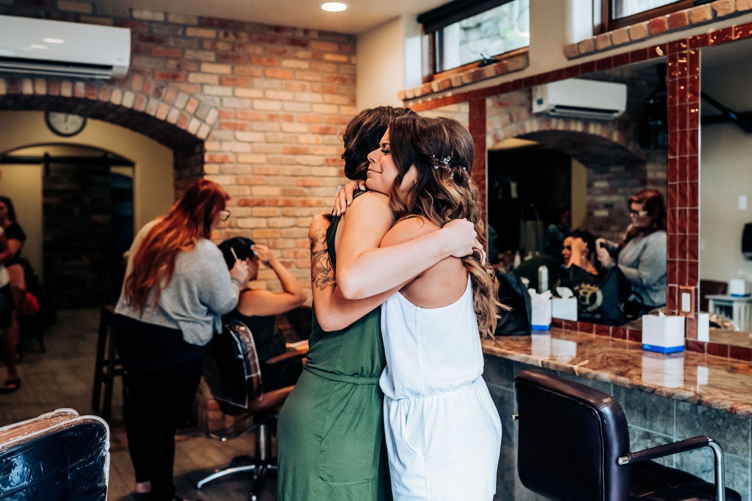 Two people embrace in an intimate moment at a rustic venue with exposed brick walls.