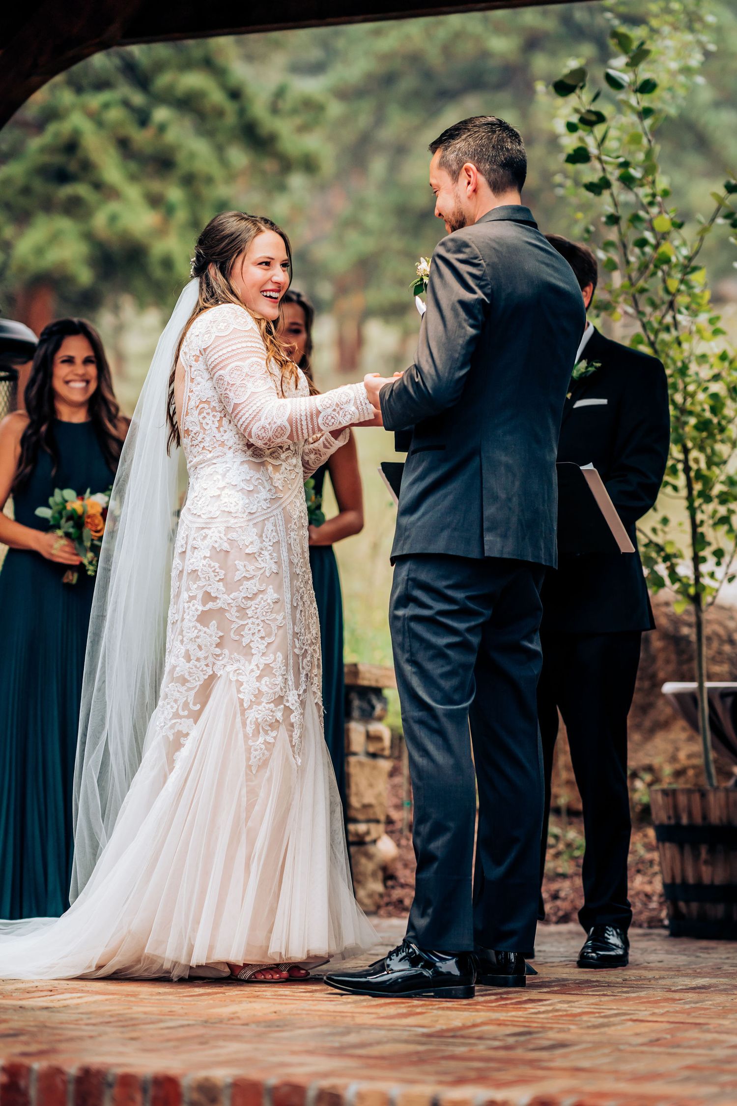 Happy couple shares a joyful moment during their wedding ceremony under a rustic pergola.