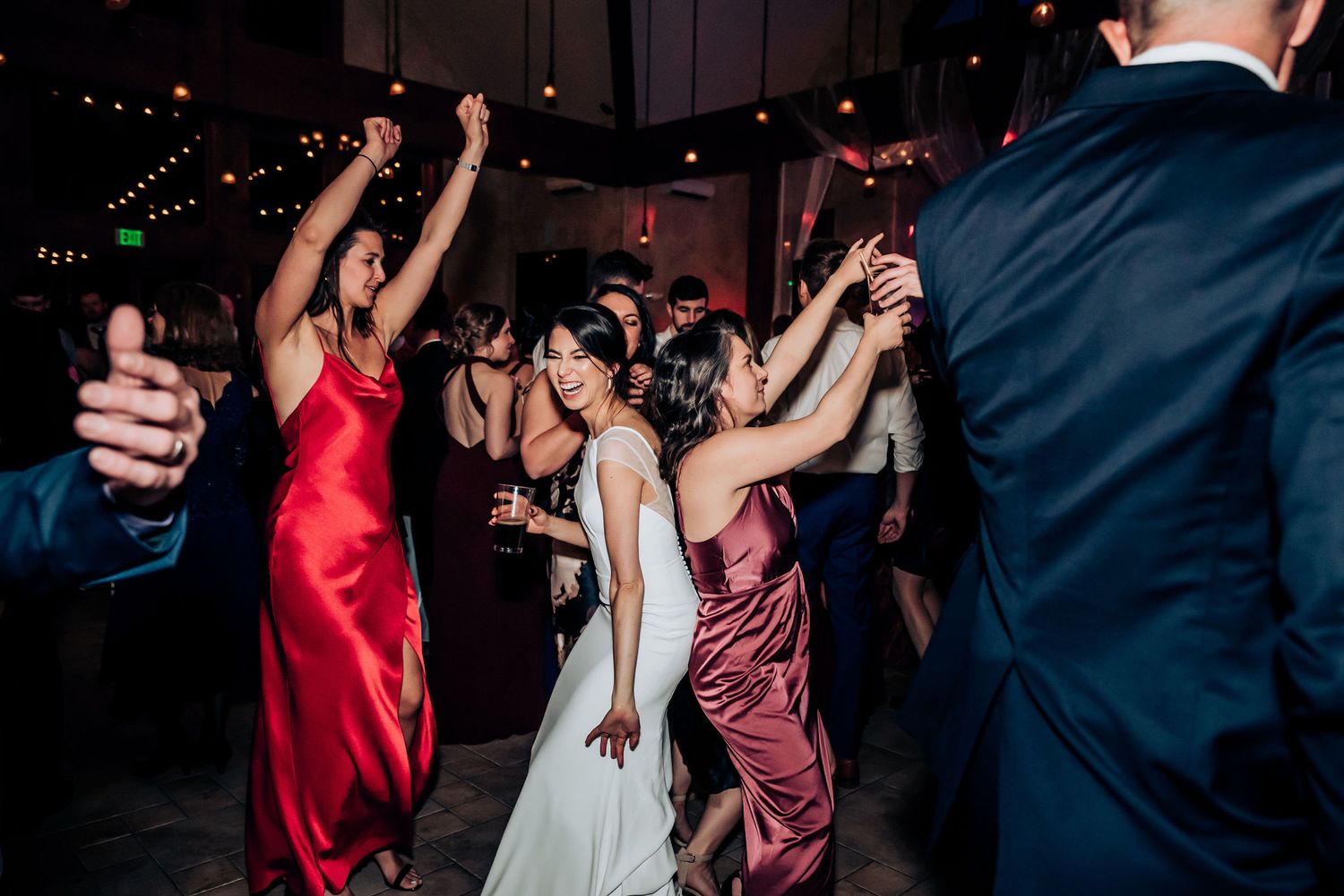 People dancing at a wedding reception with guests wearing formal dresses and suits.