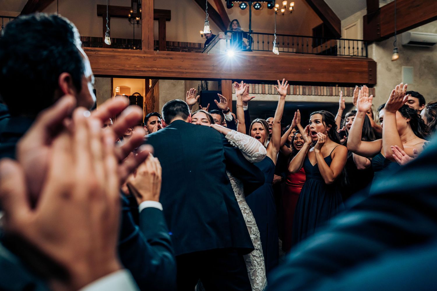 Wedding guests form a circle on the dance floor during a lively reception celebration.