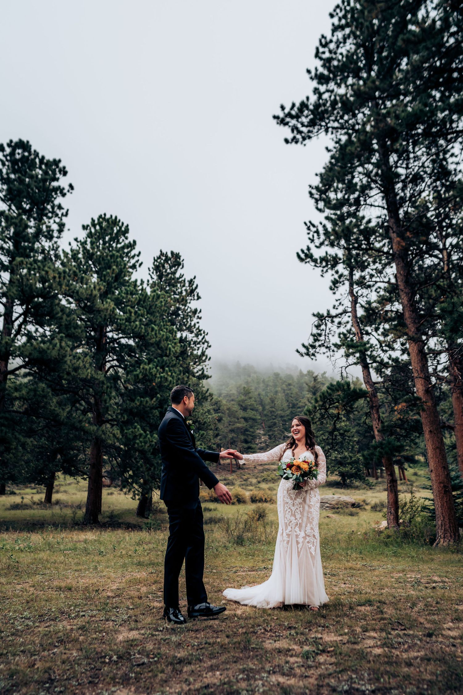 Couple shares intimate wedding moment in misty mountain forest clearing.