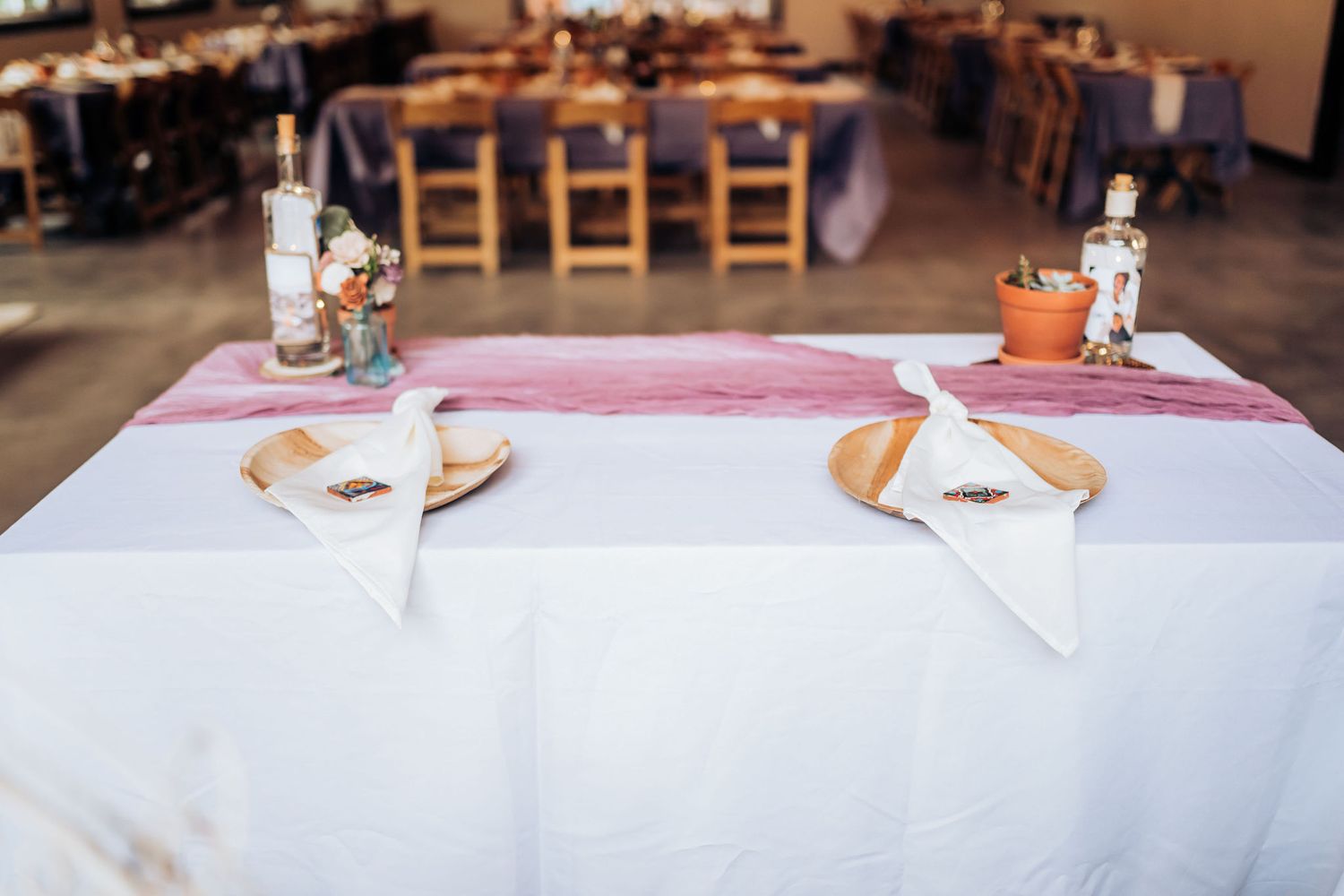 Place settings with white linens and napkins on wedding reception table.