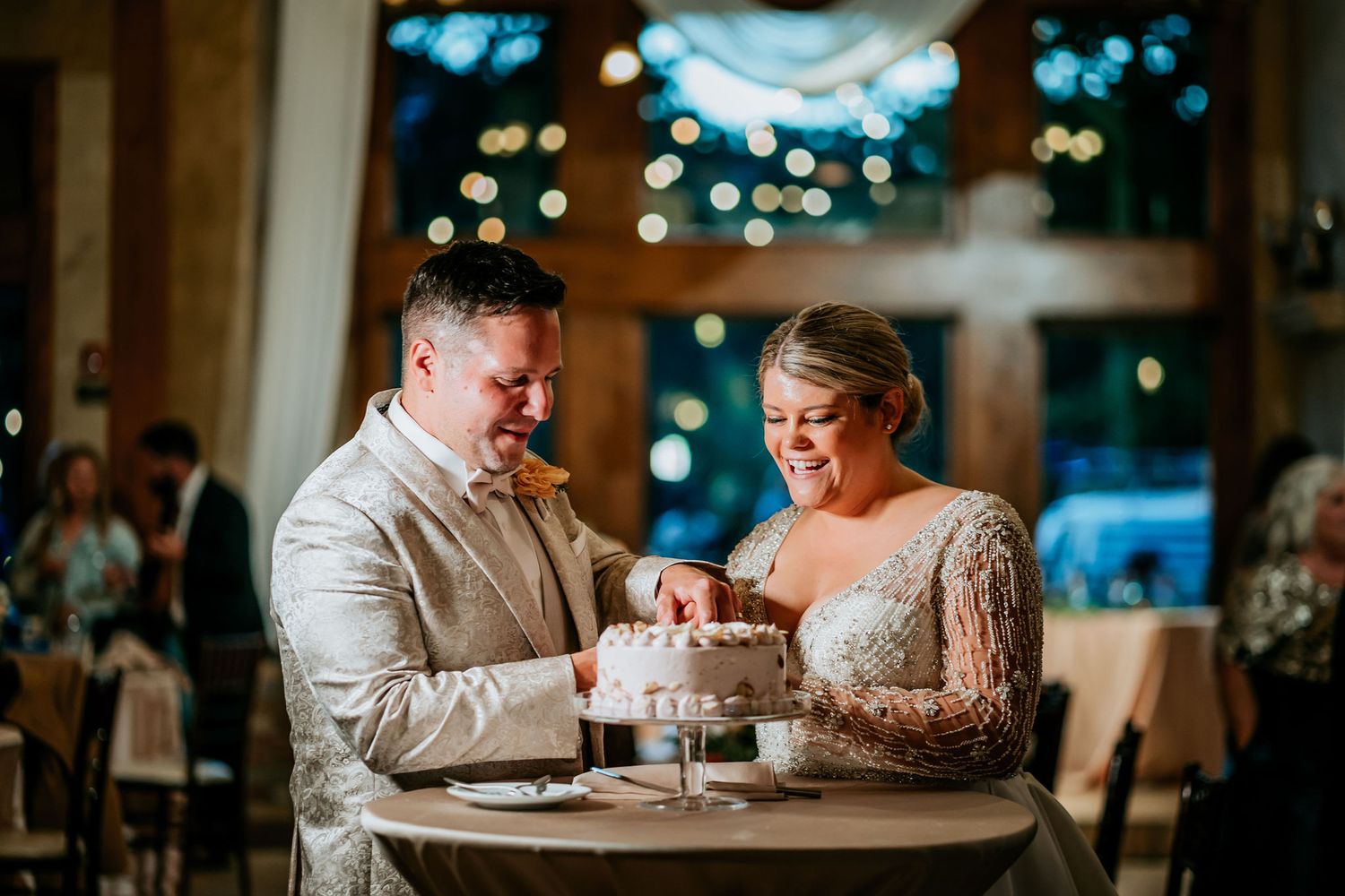 Wedding couple cutting their white wedding cake together at the reception.