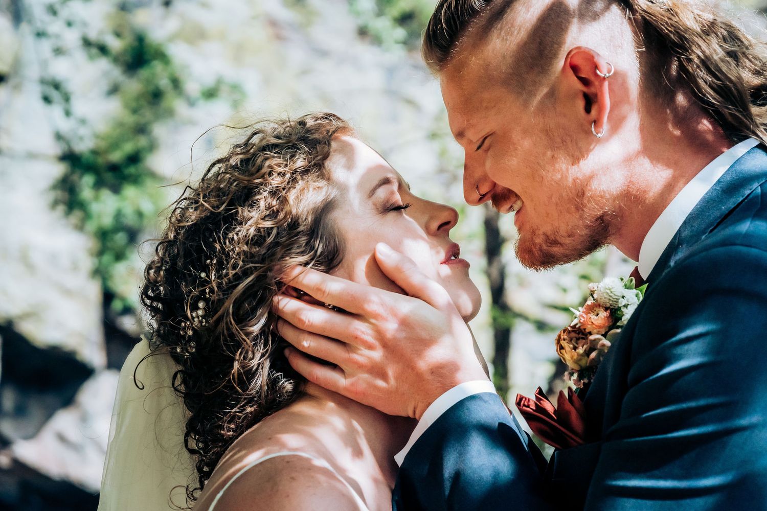 Sunlit wedding portrait capturing intimate moment between couple with natural backdrop.