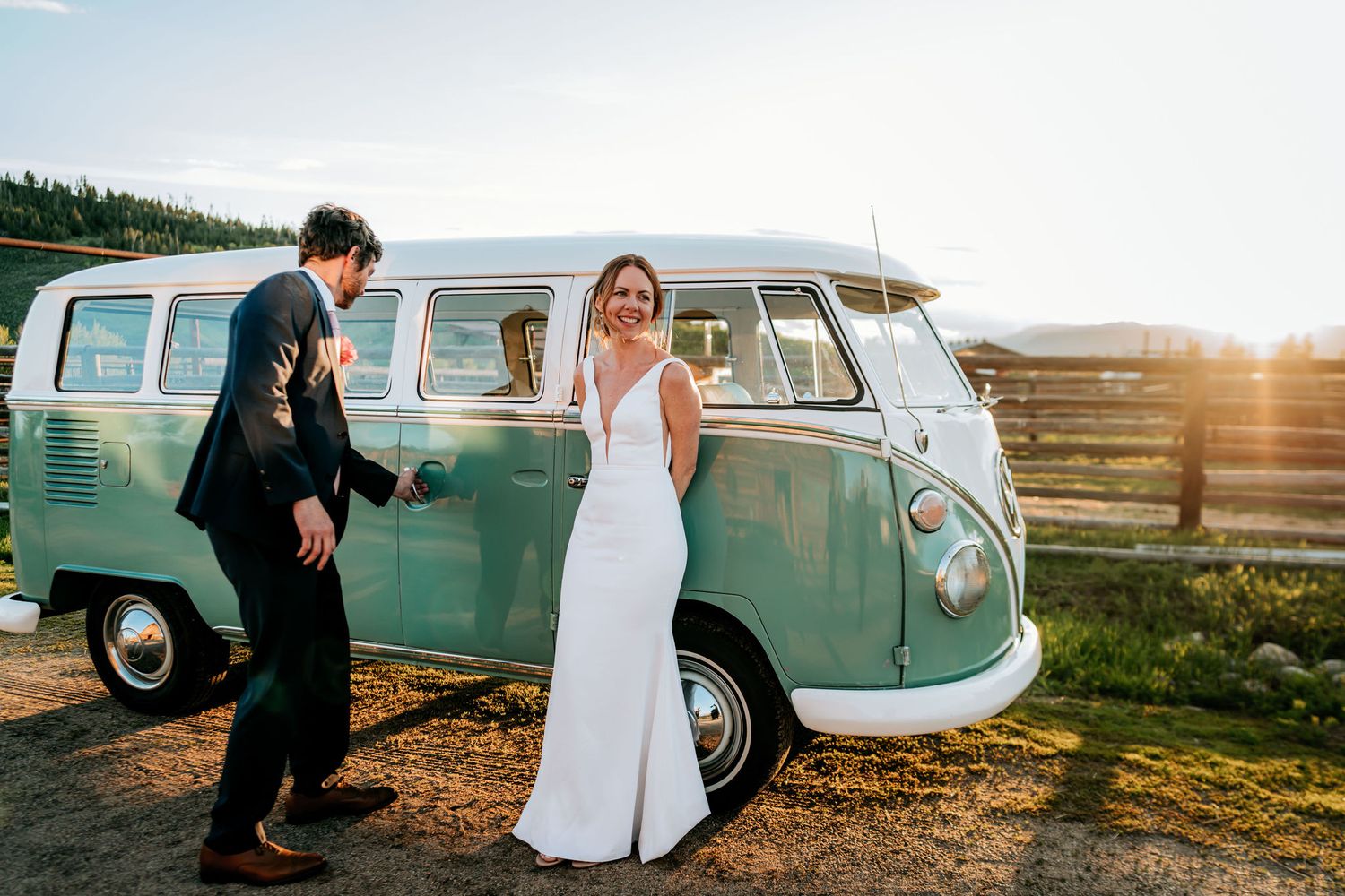 A wedding couple poses beside a mint green vintage Volkswagen bus during golden hour.