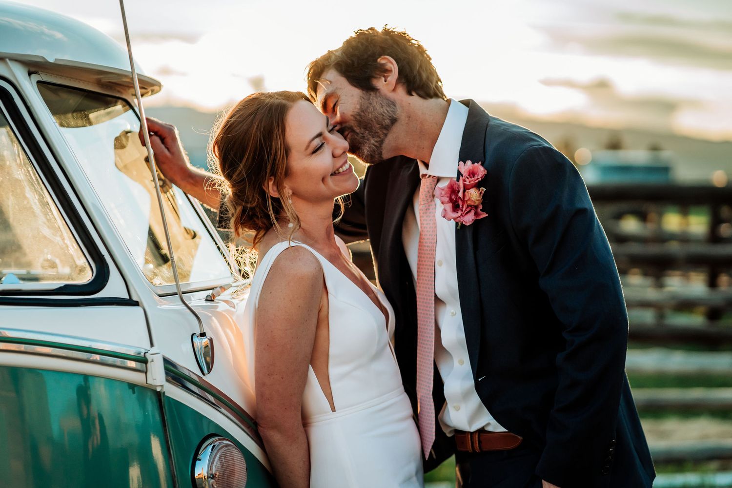 An intimate wedding moment shared beside a vintage turquoise Volkswagen van at sunset.