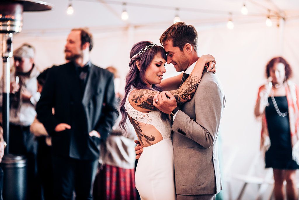Intimate slow dance moment shared during wedding reception with string lights overhead.