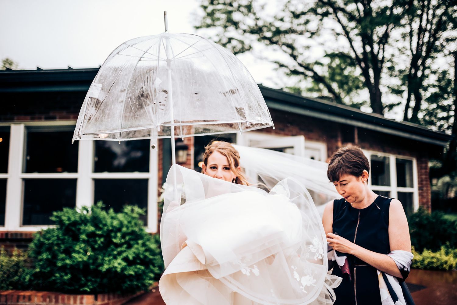 Clear umbrella shelters wedding dress during outdoor preparations.