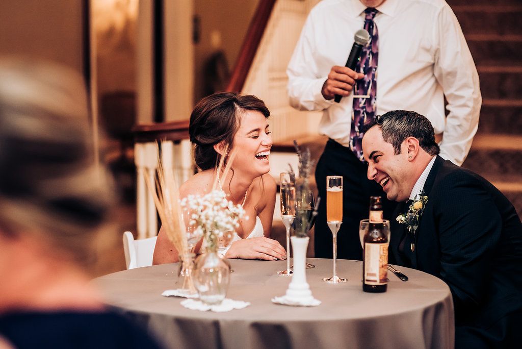 Candid reception moment with guests sharing laughter at a table.