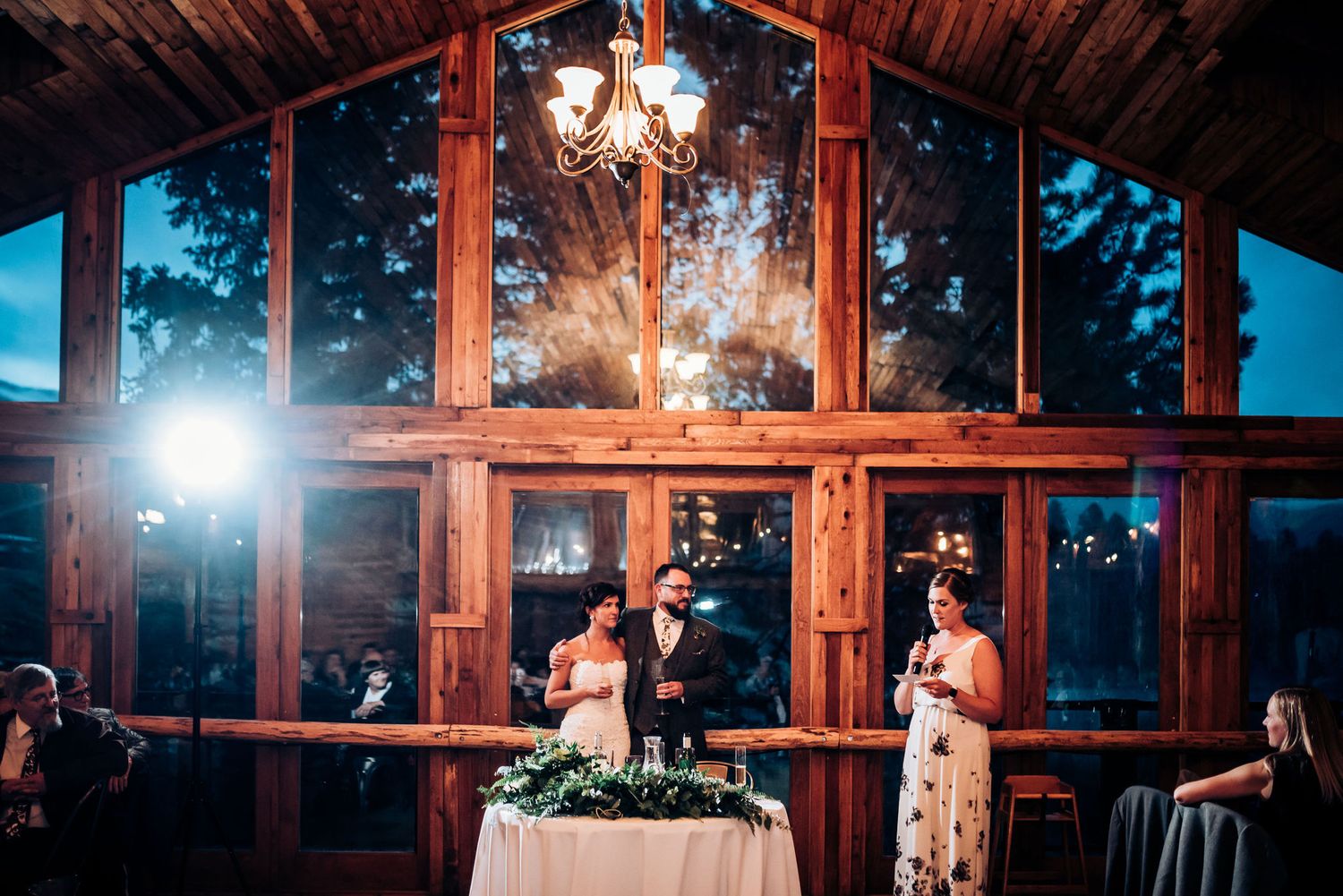Wedding celebration in rustic venue with dramatic lighting and floor-to-ceiling windows.