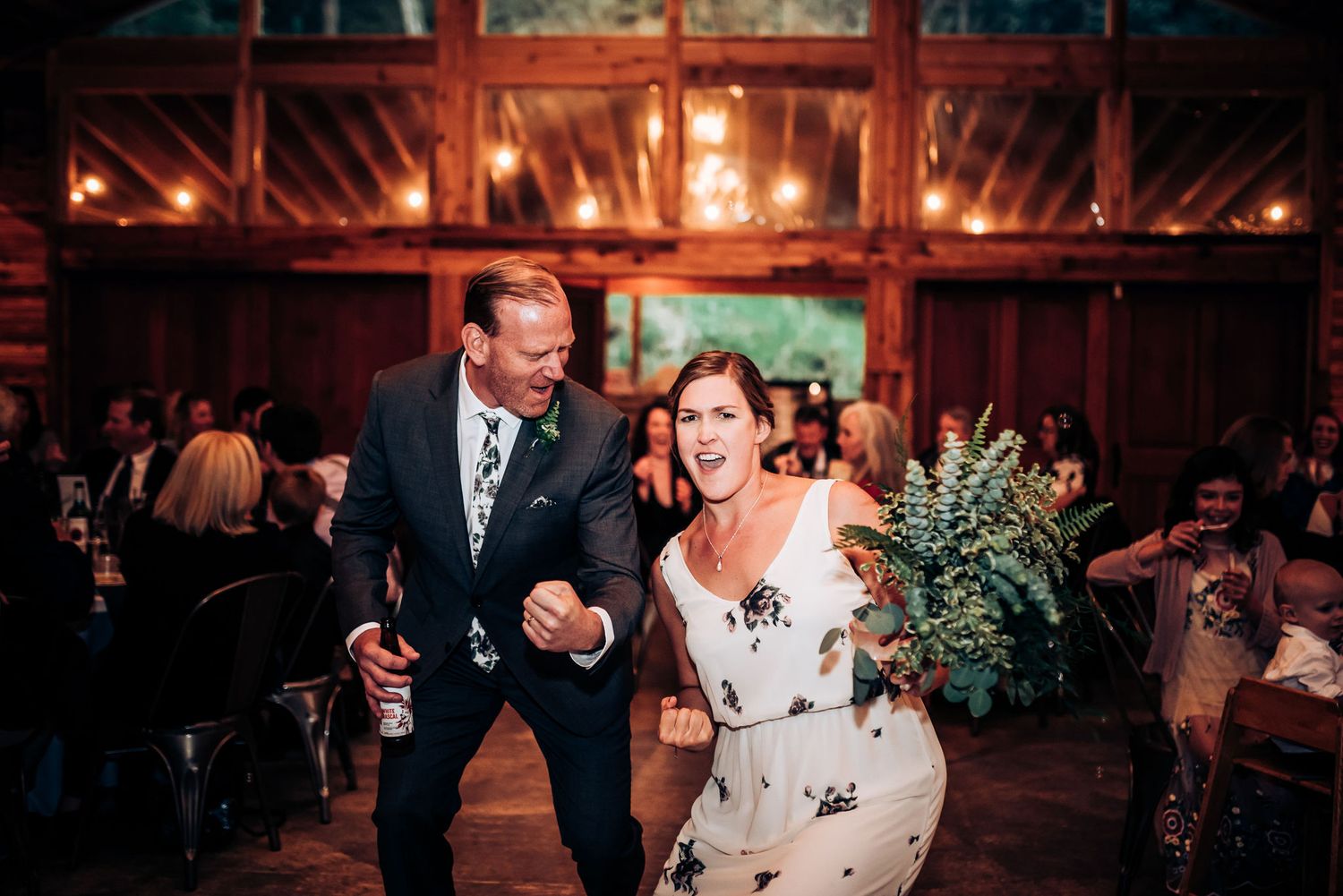Wedding reception dance floor moment in rustic barn venue with warm lighting.
