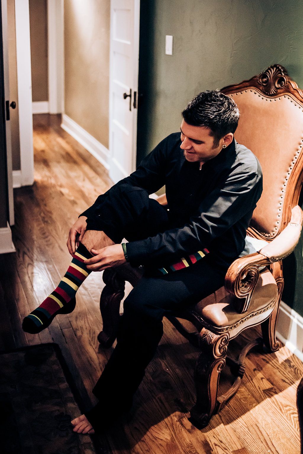 Person sitting in an ornate chair putting on colorful striped socks.