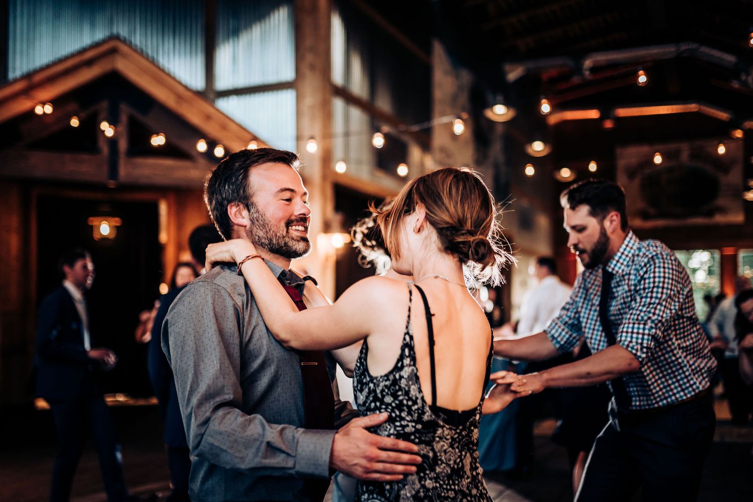 Wedding guests laughing and dancing together during a reception celebration.