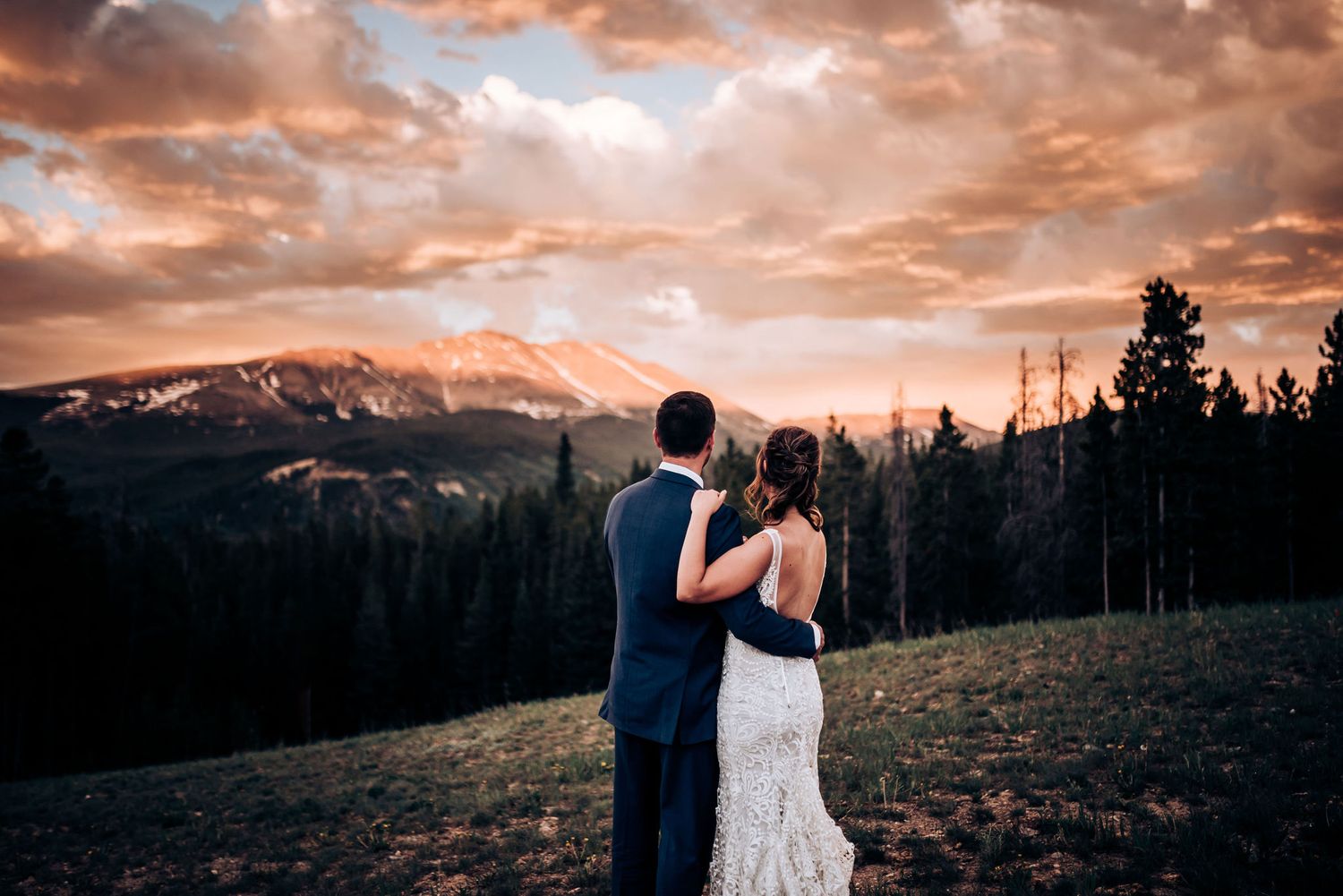 Couple admires mountain view together in formal attire during sunset.