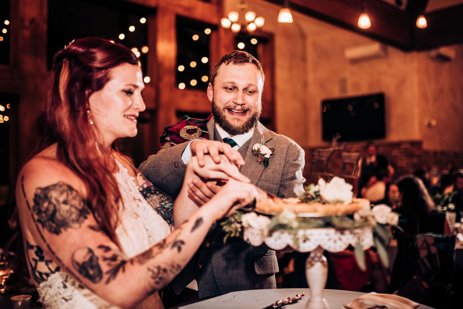 Couple cuts their wedding cake together during reception celebration.